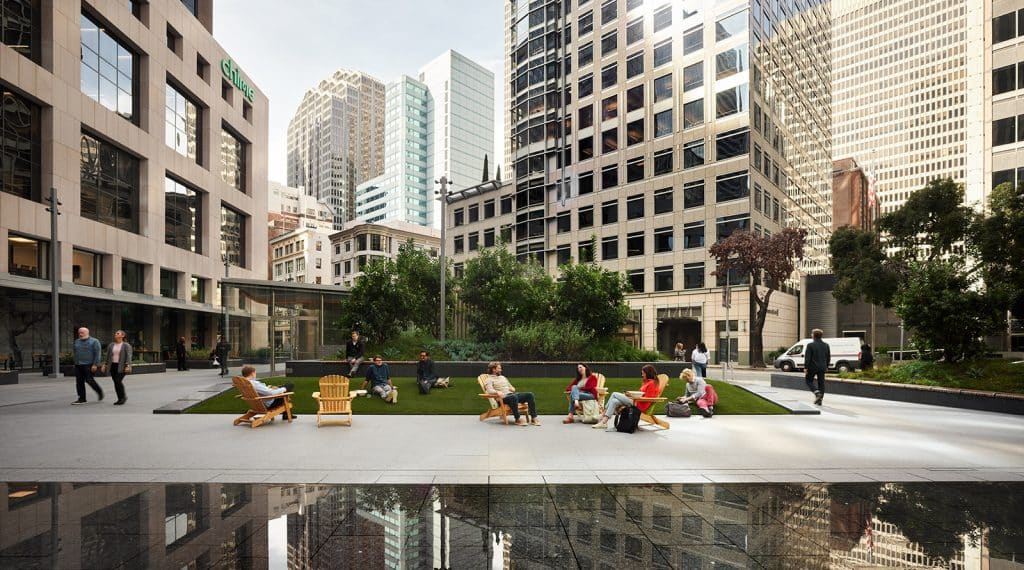 101_California_landscape-2 Modern city plaza with people relaxing on benches and chairs, surrounded by tall office buildings and green landscaping.