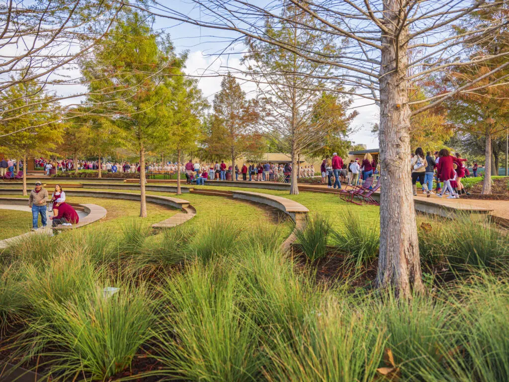 Texas A& M - Aggie Park - College Station, TX 110522 Scenic park with winding paths, trees, and people enjoying a sunny day, highlighting community and nature.